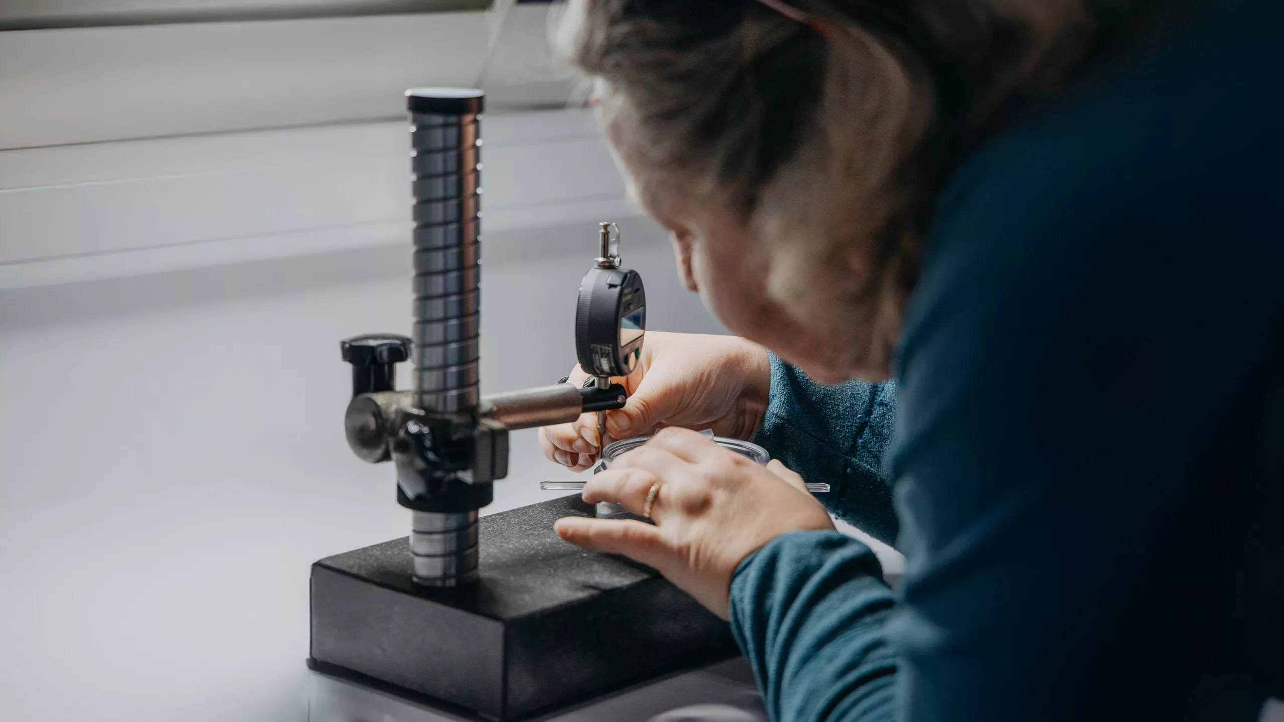Référente qualité en train de réaliser une métrologie sur une pièce plastique transparente.